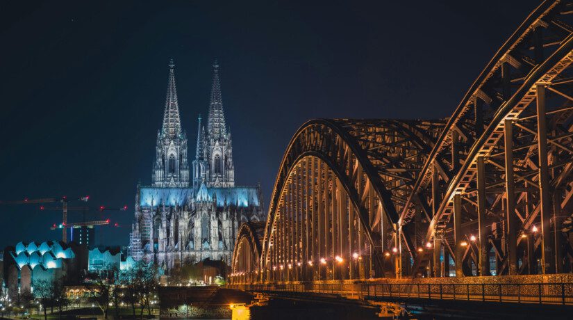 Cologne, Germany - The city's cathedral at night, with the central train station visible in the foreground.